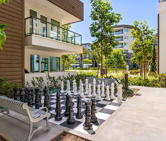 Outdoor chess board with oversized pieces and bench seating at Elements Apartments, Irvine, CA 92612