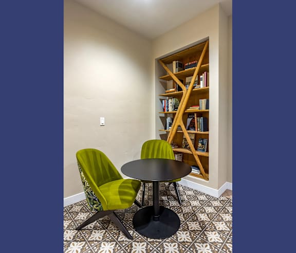 Cozy reading nook with bookshelf and velvet chairs at Elements Apartments, Irvine
