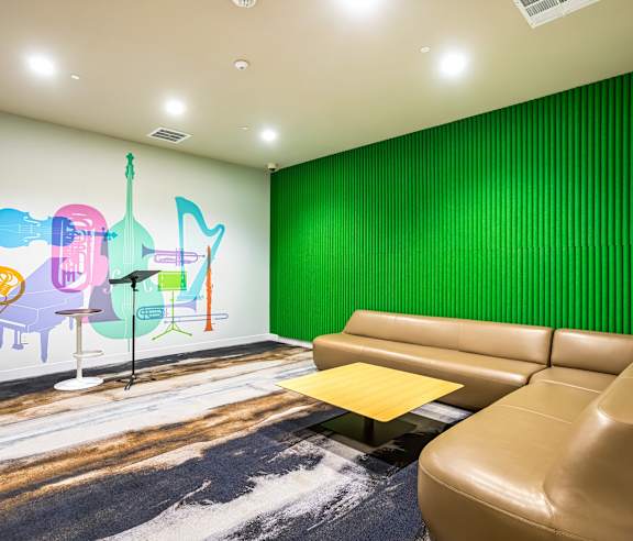 Music room with colorful wall mural and curved sofa at Elements Apartments, California