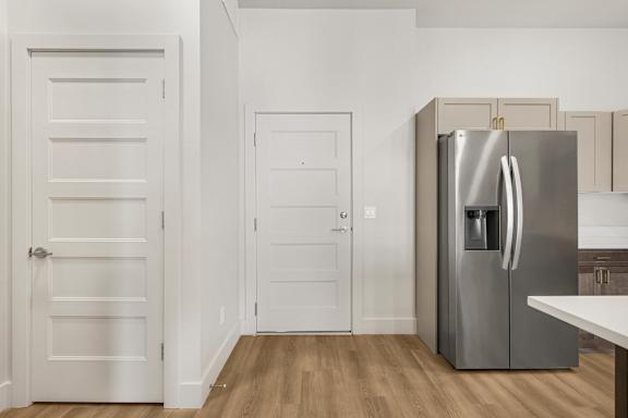 A kitchen with a refrigerator, two doors, and a counter.