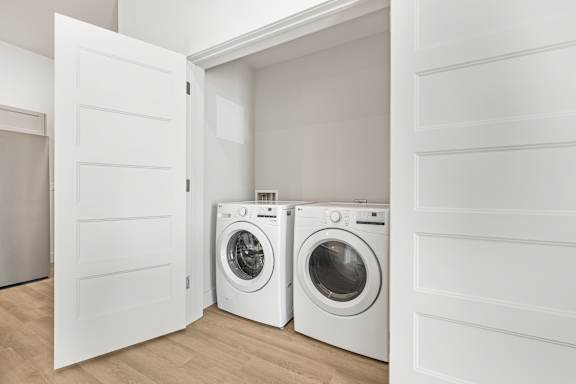 Two white front load washing machines in a laundry room.