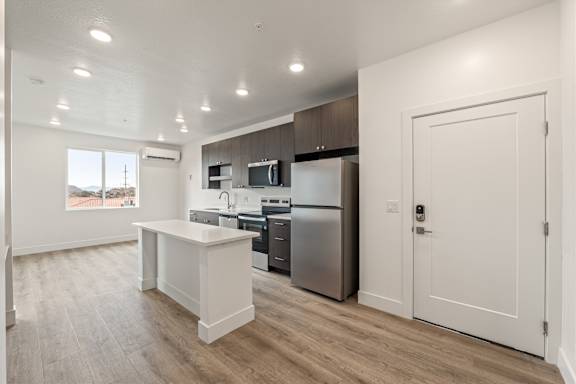 A kitchen with a white island and stainless steel appliances.