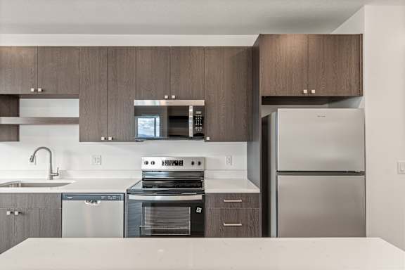 A modern kitchen with dark wood cabinets and stainless steel appliances.