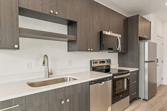 A modern kitchen with dark wood cabinets and stainless steel appliances.