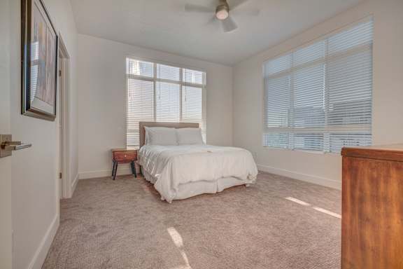 A bedroom with a bed, a small table, and a ceiling fan.