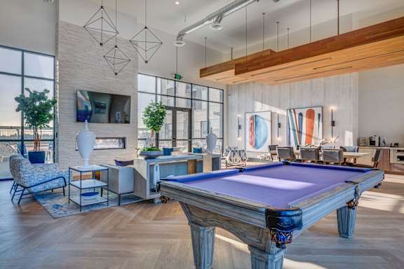 A pool table is in the middle of a room with a TV and a chair.
