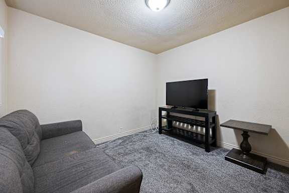 A grey sofa sits in a living room with a television and a small table.
