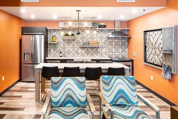 A kitchen with orange walls and a white table with chairs.
