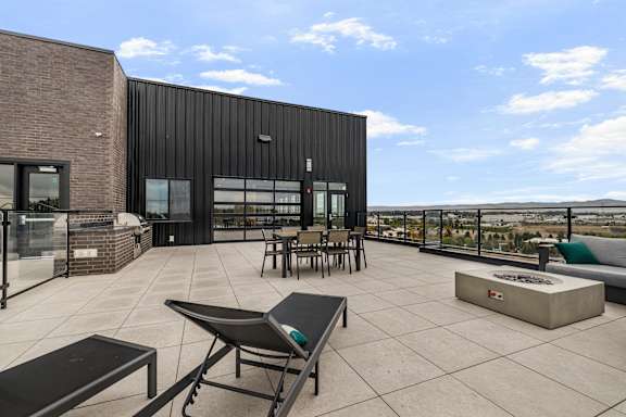 A patio area with a table and chairs overlooking a cityscape.