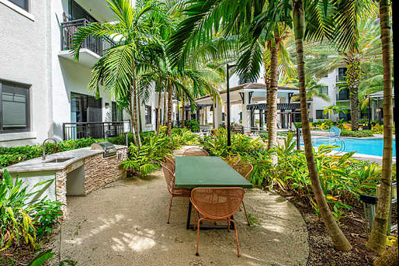 A patio with a table and chairs surrounded by palm trees.