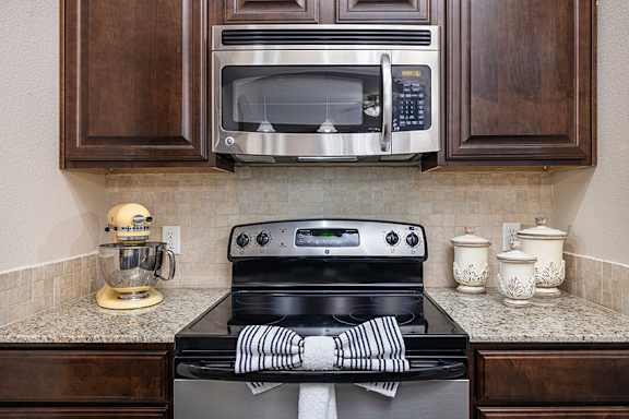A kitchen with a black stove top oven and a silver microwave above it.
