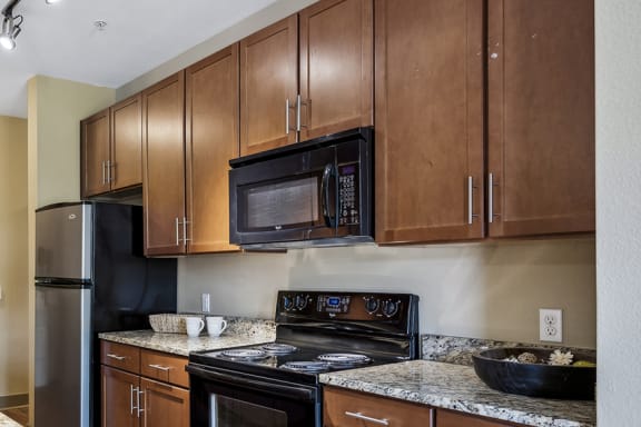 Custom 42-inch espresso-colored kitchen cabinetry - Acadia at Cornerstar Apartments