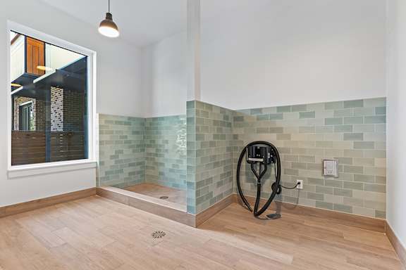 A bathroom with a tiled wall and a wooden floor.
