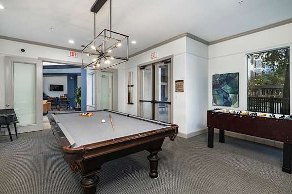 A pool table in a room with a view of trees outside the window.
