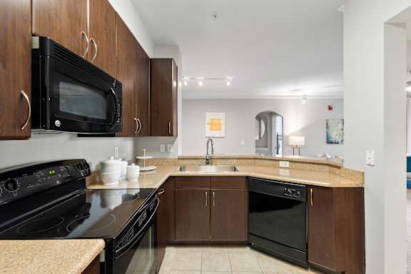 A kitchen with black appliances and brown cabinets.