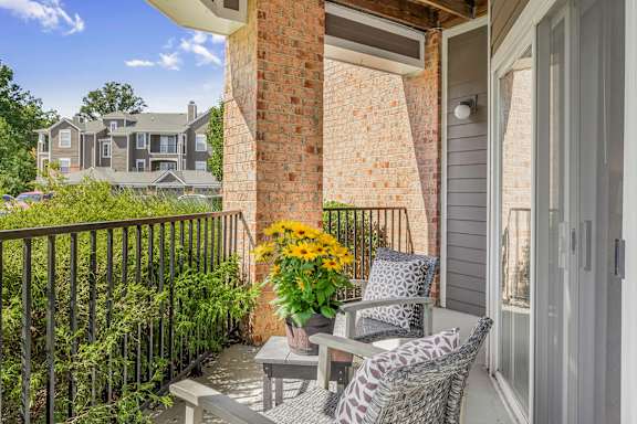 A balcony with a table and chairs overlooking a residential area.