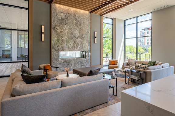 A modern living room with a large grey sofa and a stone wall.
