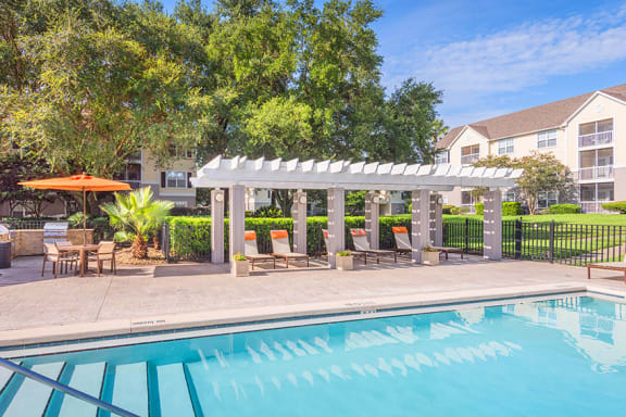 The Colony at Deerwood Apartments - Resort-style swimming pool with pergola and grilling area
