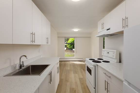 A kitchen with white cabinets and a stove top oven.