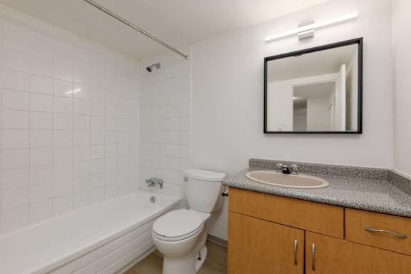 A white toilet sits next to a white bathtub in a bathroom.