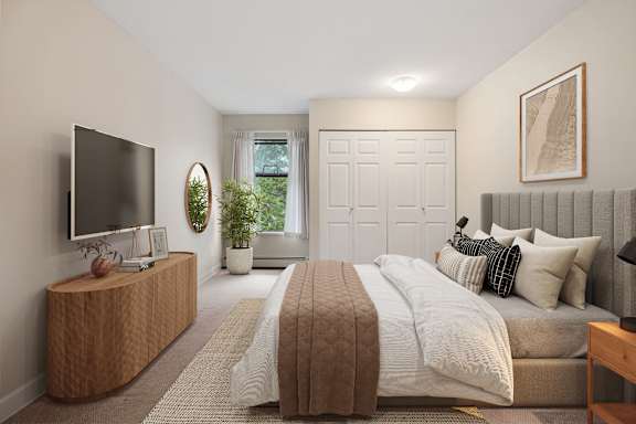 A bedroom with a large bed and a flat screen TV on a wooden cabinet.