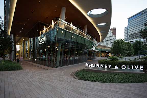McKinney & Olive storefront with a curved roof and glass doors. at Uptown by Onni Apartments, Apartments, Dallas, TX