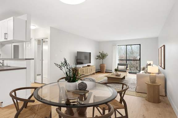 A modern living room with a glass table and brown chairs.