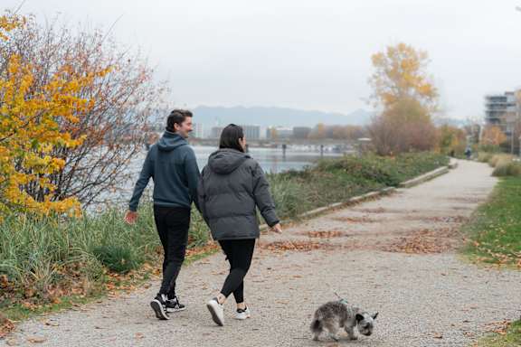 A man and a woman are walking a dog on a path.