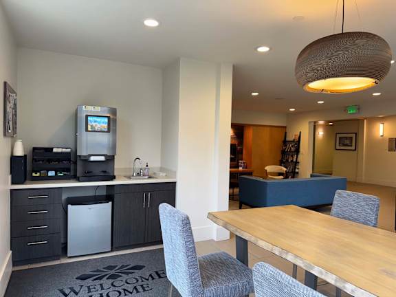 A kitchen area with a coffee machine and a fridge.