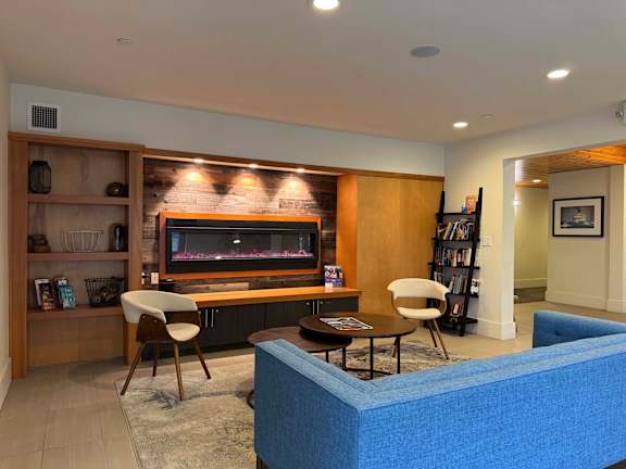 A living room with a blue couch, a wooden entertainment center, and a fireplace.