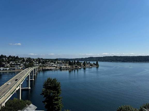 A bridge over a calm body of water with a city in the background.