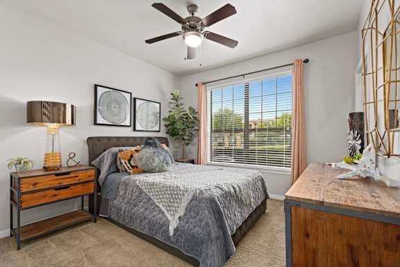 A bedroom with a bed, nightstand, and window.
