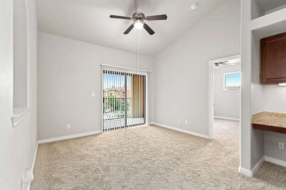 A room with a ceiling fan and carpeted floor.