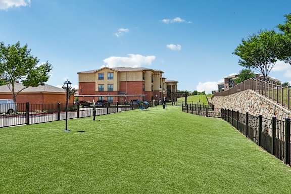 A grassy area in front of a building with a black fence.