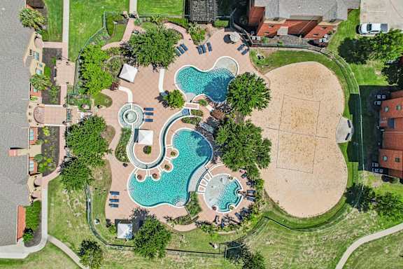 An aerial view of a park with a swimming pool and a sandy area.