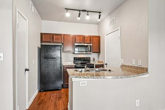 A kitchen with a black refrigerator, microwave, and stove.