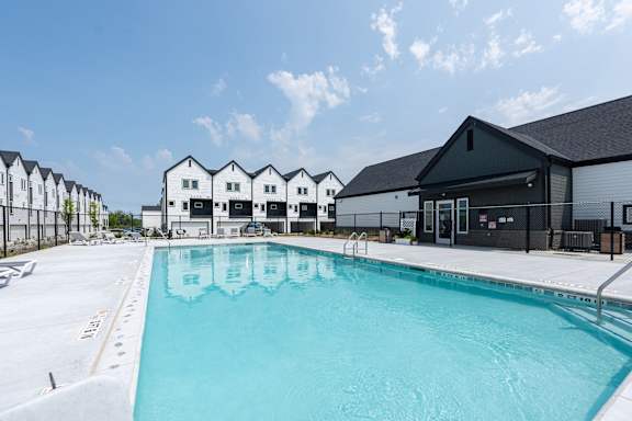 A swimming pool in front of a building with a clear blue sky.
