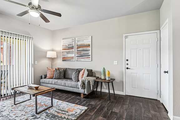 A living room with a grey couch, a coffee table, and a ceiling fan.
