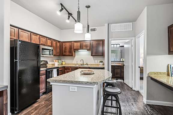 A kitchen with a black fridge and wooden cabinets.