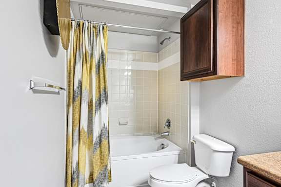 A bathroom with a white toilet and a shower curtain with a yellow and grey pattern.
