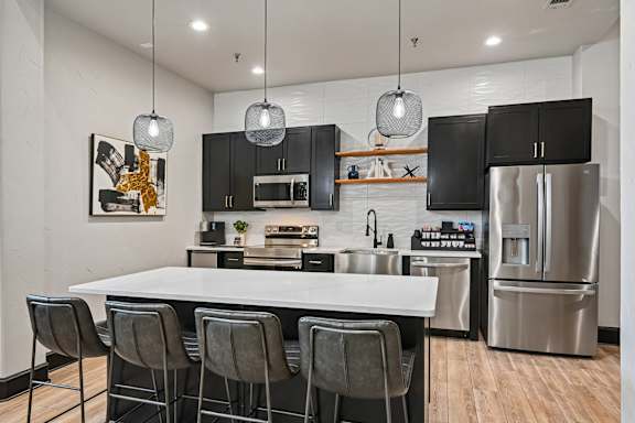 A modern kitchen with a white island and black cabinets.