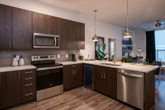 Kitchen with dark wood cabinets, stainless steel appliances, and a built-in beverage cooler at The Apex at CityPlace, Overland Park