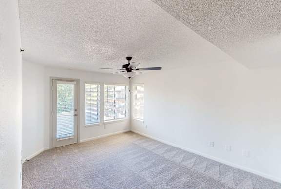 A room with a ceiling fan and a door leading outside.