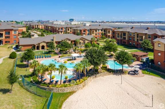 A large apartment complex with a pool and beach volleyball court.