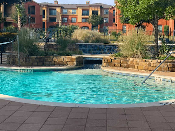 A swimming pool surrounded by a brick wall and a building in the background.