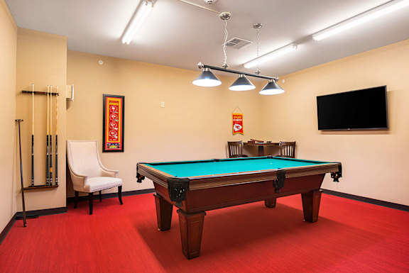 A pool table in a room with a chair and a television.
