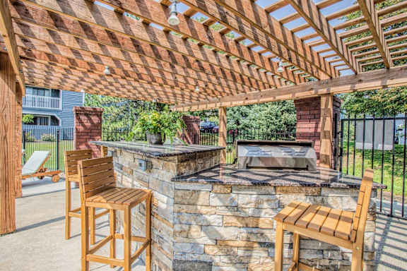 A wooden patio with a stone fireplace and two chairs.