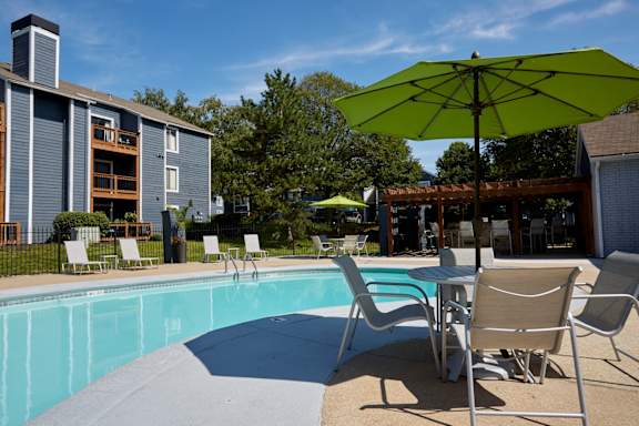 A pool area with chairs and an umbrella.