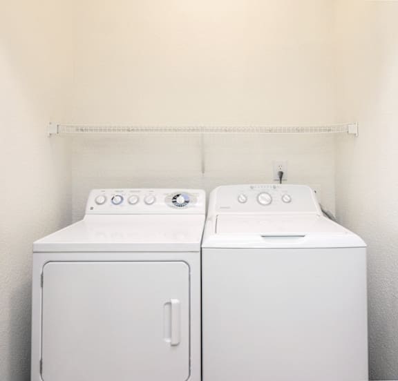 Two white washing machines in a small laundry room.