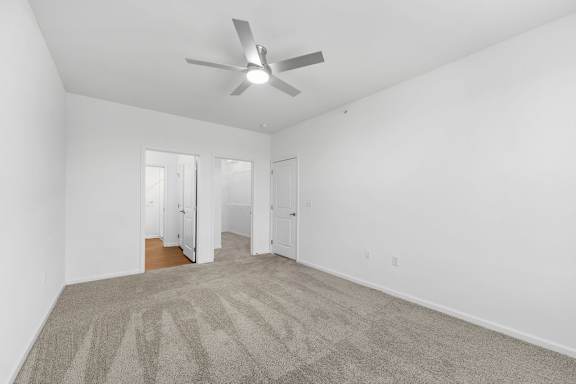 A room with a ceiling fan and carpeted floor.